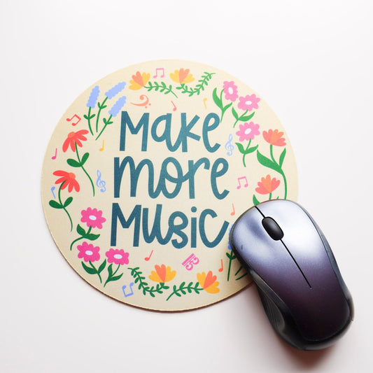 Mouse pad with 'Make more music' text and floral designs on a white surface with a computer mouse.