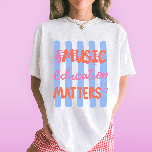 Person wearing a white t-shirt with 'Music Education Matters' text on a pink background