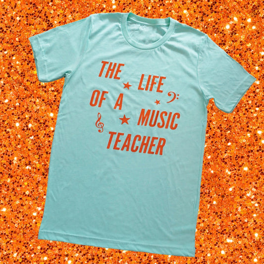 The Life of a Music Teacher Shirt with a background of orange sparkles